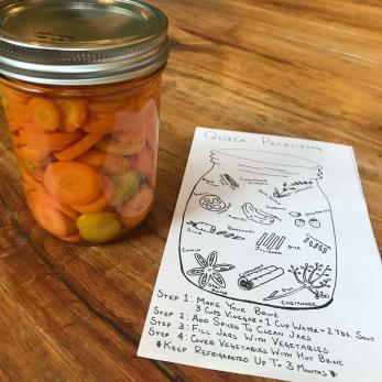 Pickled carrots sit next to a pickling recipe on a counter